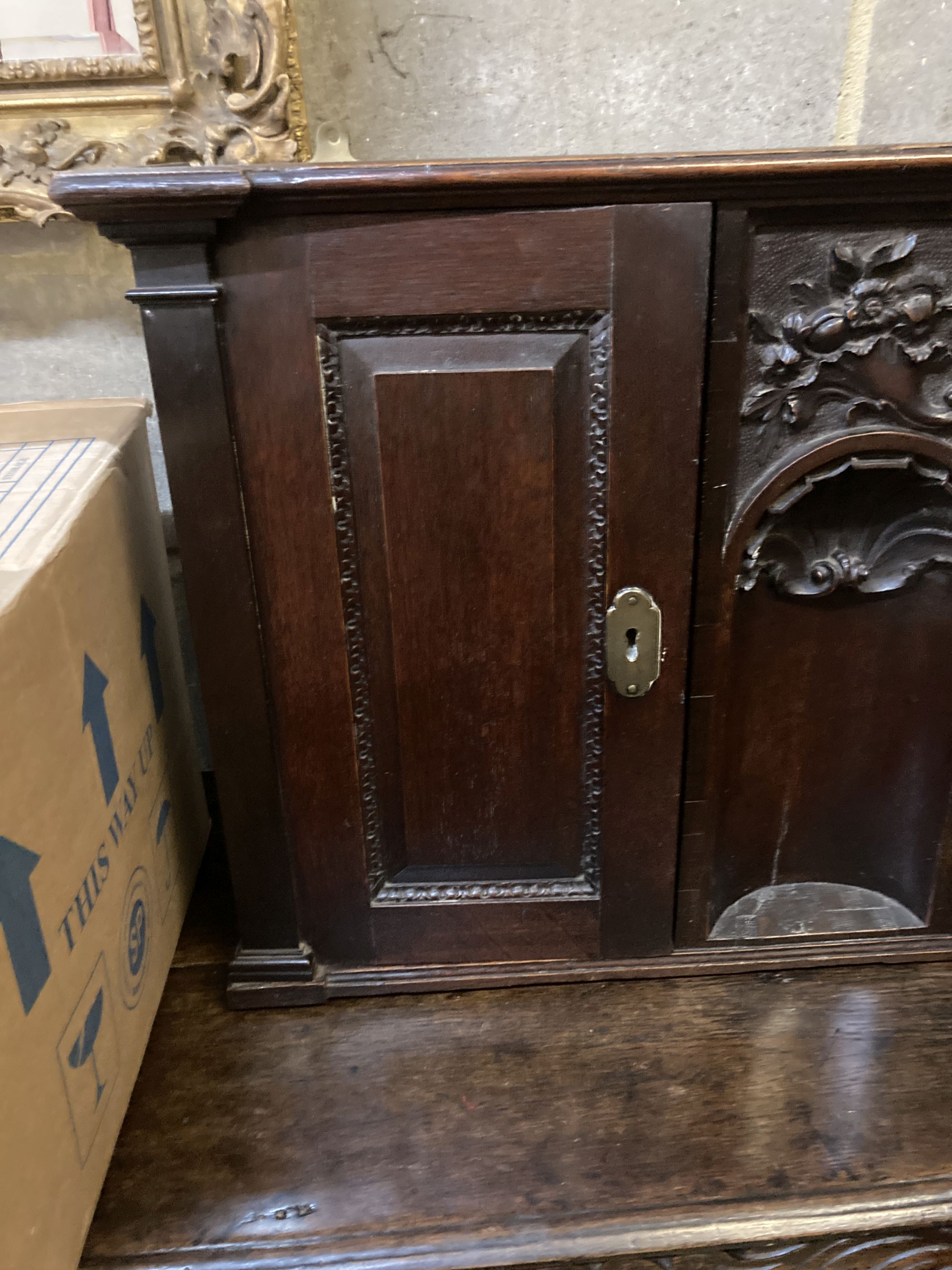 An 18th century style carved oak two door wall cabinet, with concealed central compartment, width 80cm, depth 19cm, height 50cm